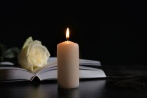 Candle stands near bible and white rose to pay tribute to victim of wrongful death accident